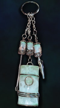 a silver key chain with a green stone on it